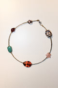 A silver-toned beaded necklace with five distinct decorative beads, including a turquoise rectangular bead, a red faceted bead, a striped striped bead, a pink flower-shaped bead, and a red and black marbled bead, displayed on a plain off-white background.